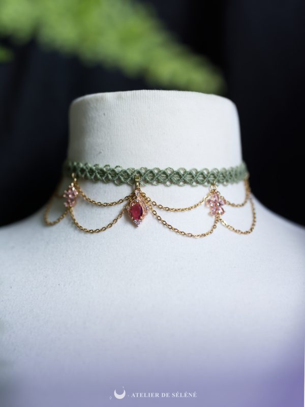 collier ras de cou avec un tissage vert , des chaines dorées et des pendentif fleur rose fait main par atelier de selene
